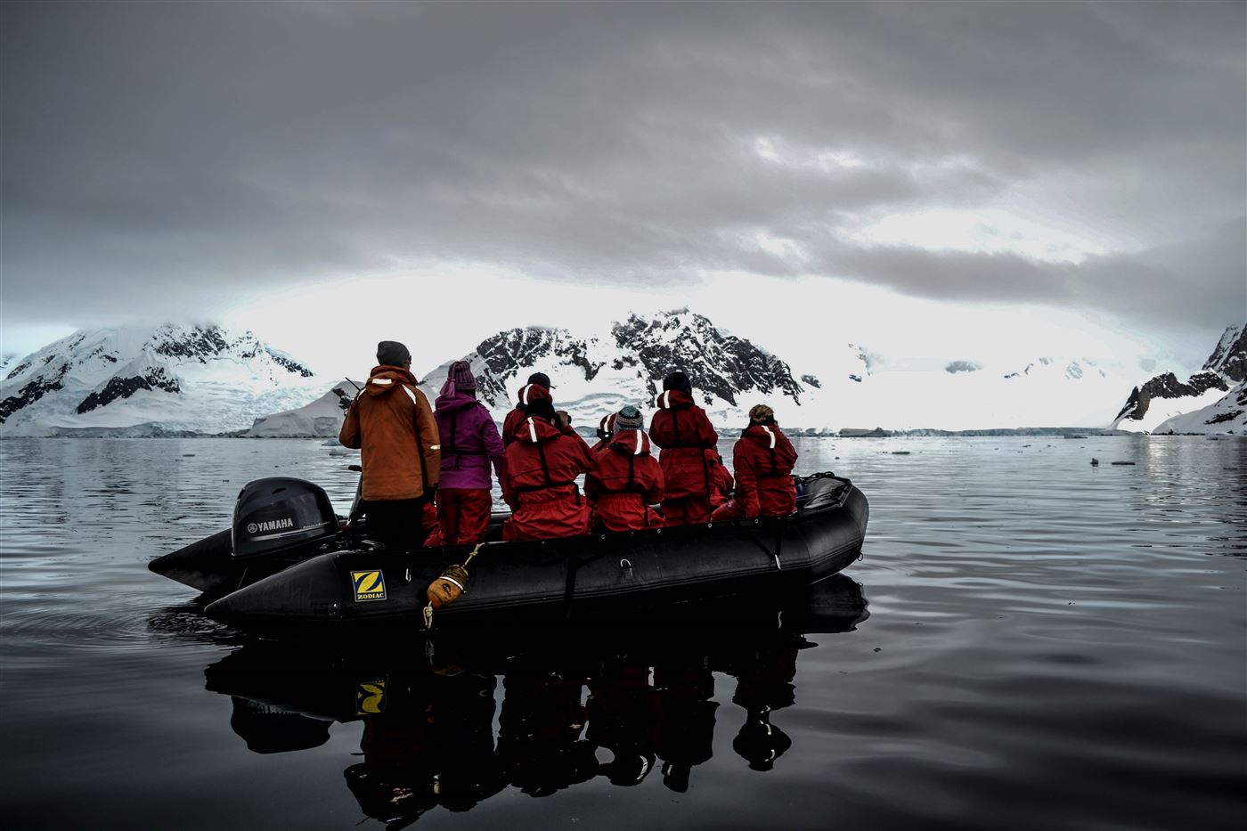 Expedition passengers wearing full layered cold-weather gear and life jackets aboard a Zodiac in Antarctica